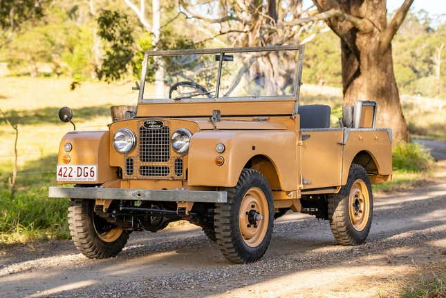 A beige series 1 land rover 80" is parked on a gravel road