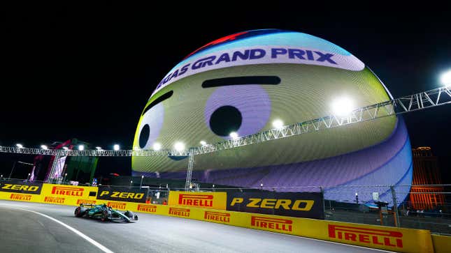 Aston Martin Racing driver Fernando Alonso (14) of Spain races past the Sphere displaying a smiley face wearing a race helmet whose watching the action during qualifying for the Formula 1 Heineken Silver Las Vegas Gran Prix on November 18, 2023 on the Las Vegas Street Circuit in Las Vegas, Nevada.